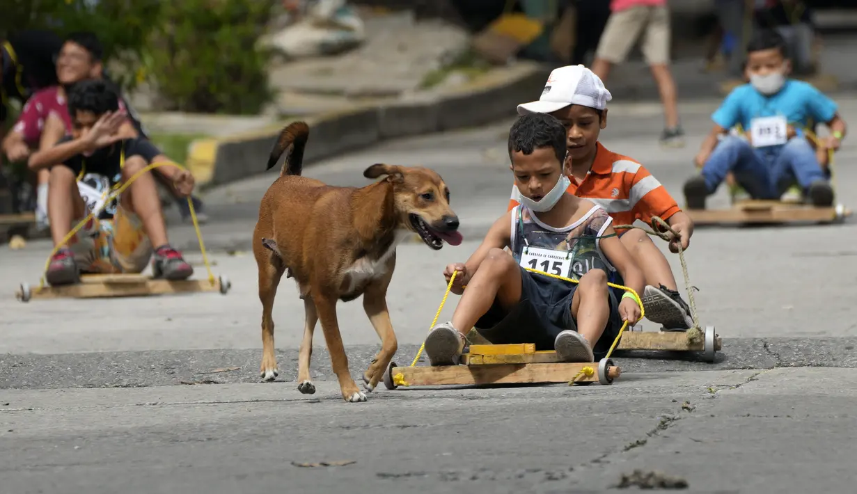 Anak-anak berpartisipasi dalam perlombaan jalanan tradisional "carruchas", sebutan untuk mobil kayu darurat di Caracas, Venezuela, Sabtu (18/12/2021). Anak-anak menikmati perlombaan yang menandai 10 tahun melestarikan tradisi ini. (AP Photo/Ariana Cubillos)