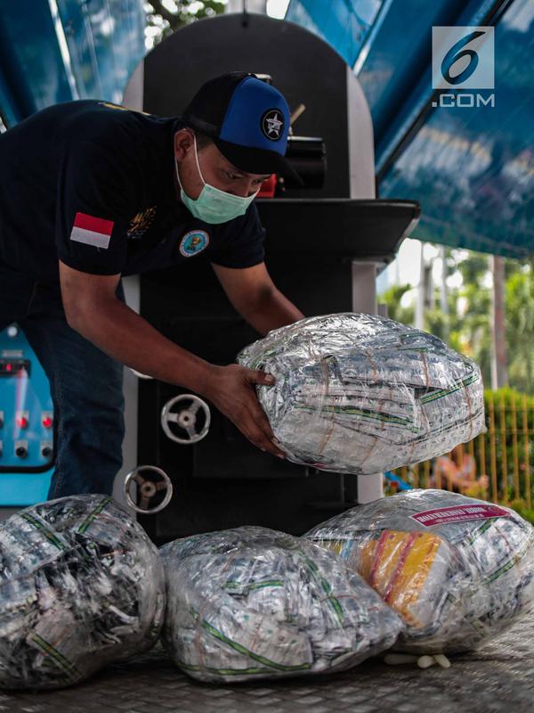 Petugas bersiap memasukkan barang bukti psikotropika ke dalam alat pembakar di Kejaksaan Negeri Jakarta Barat, Selasa (11/12). Barang bukti yang dimusnahkan berupa senjata Api, psikotropika, makanan, obat-obatan dan kosmetika. (Liputan6.com/Faizal Fanani)