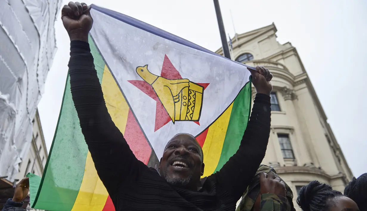 Demonstran membawa bendera nasional Zimbabwe dalam aksi protes di luar Kedutaan Besar Zimbabwe di London, Sabtu (18/11). Komunitas warga Zimbabwe menggelar aksi long march menyerukan teriakan agar Presiden Robert Mugabe mundur. (NIKLAS HALLE'N/AFP)
