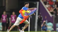 Seorang pria membawa bendera pelangi yang identik dengan LGBT berlari melintasi lapangan selama pertandingan grup H Piala Dunia 2022 Qatar antara Portugal melawan Uruguay di Stadion Lusail di Lusail, Qatar, Senin, 28 November 2022.  Pria itu berada di lapangan selama sekitar 30 detik, sebelum akhirnya dikawal oleh petugas keamanan. (AP Photo/Themba Hadebe)