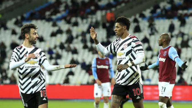 Penyerang Manchester United, Marcus Rashford (kanan) berselebrasi dengan rekannya Bruno Fernandes pada pertandingan lanjutan Liga Inggris di stadion London di London, Inggris, Minggu (6/12/2020). MU menang 3-1 atas West Ham. (Adam Davy / Pool via AP)