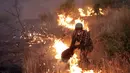 Seorang pria memadamkan api di lapangan di luar desa Sao Jose das Matas, dekat Macao, Portugal tengah, (26/7). Lebih dari 2.300 petugas pemadam kebakaran menangani kebakaran tersebut. (AP Photo/Armando Franca)
