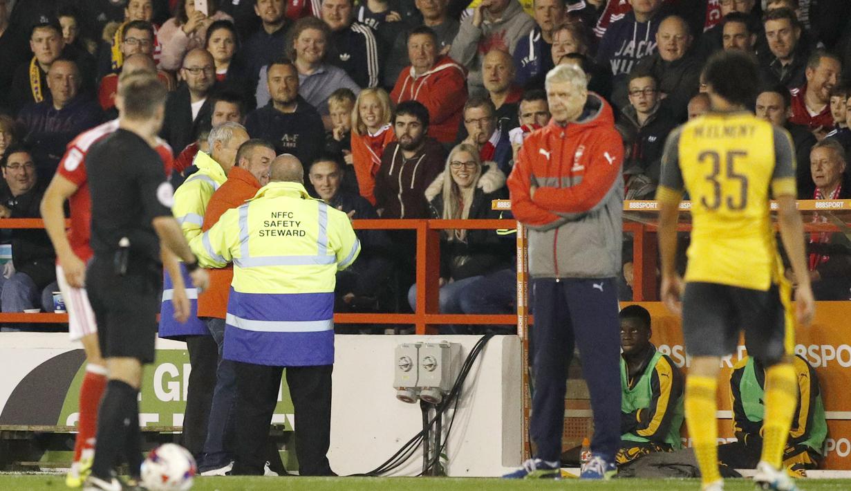 Petugas keamanan menahan seorang fans yang masuk ke lapangan saat  Arsenal melawan Nottingham Forest pada putaran ketiga Piala Liga Inggris di Stadion The City Ground, Rabu (21/9/2016) dini hari WIB. (Action Images via Reuters/John Sibley)