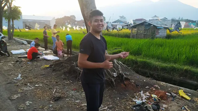Vicky, salah satu pehobi layangan, nampak tersenyum sambil menari benang layangan yang tengah ia mainkan bersama warga lainnya di Garut, Jawa Barat.