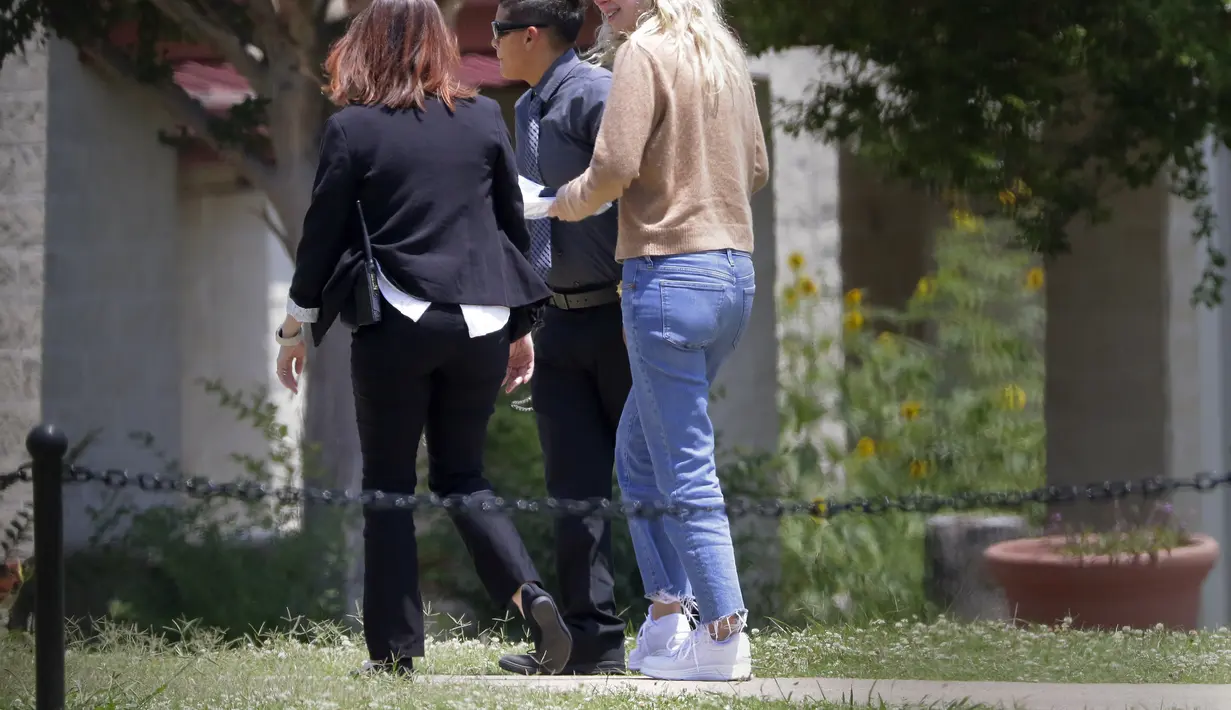 Holmes, 39 tahun, terlihat dari luar gerbang penjara berjalan masuk ke dalam kamp penjara wanita federal mengenakan celana jeans, sweter coklat dan tersenyum saat berbicara dengan dua pegawai penjara yang menemaninya. (AP Photo/Michael Wyke)