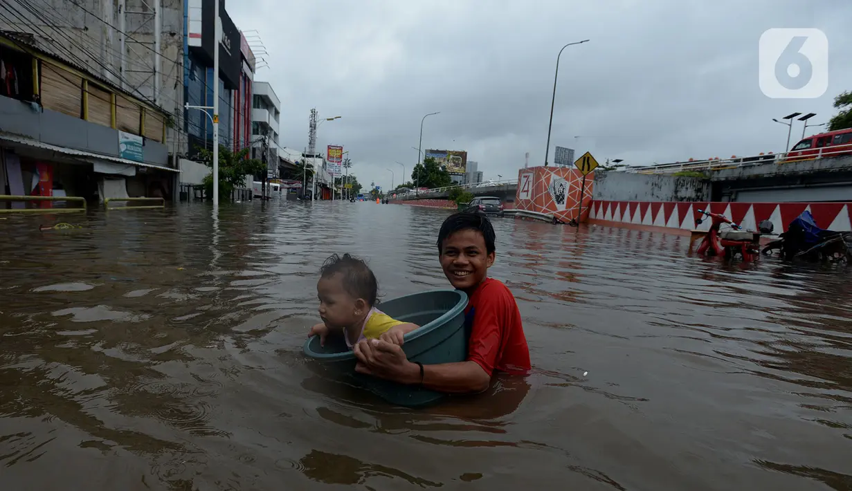 Warga RW 04 Kelurahan Jelambar melintasi banjir di Jakarta, Rabu (1/1/2020). Hujan yang turun saat pergantian tahun baru 2019-2020 menyebabkan sejumlah titik di kawasan Grogol terendam banjir. (merdeka.com/Imam Buhori)