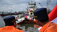 Dua orang petugas Basarnas memperhatikan kondisi bangkai badan pesawat Airasia QZ8501 yang berhasil dievakuasi, Pelabuhan Tanjung Priok, Jakarta, Senin (2/3/2015). (Liputan6.com/Faizal Fanani)