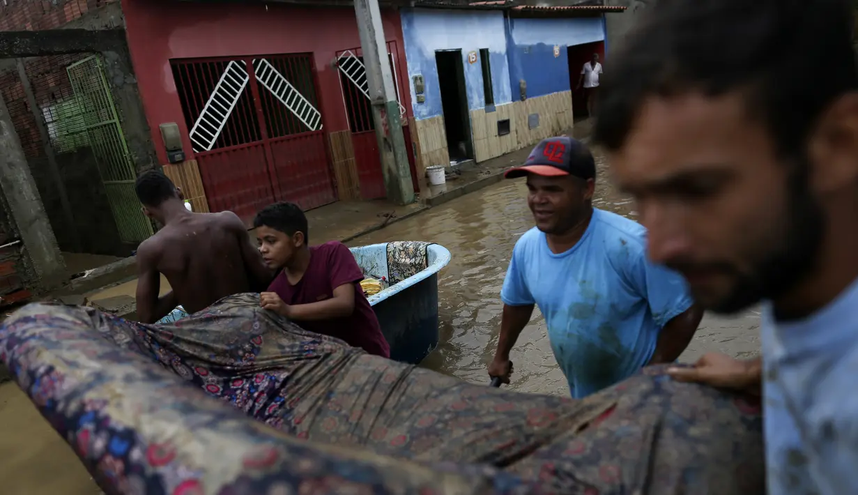 Warga membawa sofa saat membersihkan rumah mereka yang terendam banjir di Itapetinga, negara bagian Bahia, Brasil, Selasa (28/12/2021). Dua bendungan jebol pada Minggu (26/12) di timur laut Brasil, mengancam banjir yang lebih parah di wilayah yang diguyur hujan. (AP/Raphael Muller)