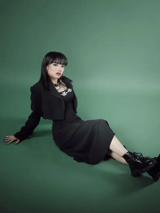 Dalam sebuah photoshoot, Fuji juga tampak mengenakan blazer hitam dengan gayanya sendiri. Cropped blazer hitam dipadu dengan off-the-shoulder dress yang sama-sama berwarna hitam. Dress ini memiliki detail taburan payet batu berkilauan yang menambah kesan glamor pada warna monokrom hitam. Fuji juga menyempurnakan keseluruhan tampilannya dengan kalung yang besar dan makeup bold. Foto: Instagram.