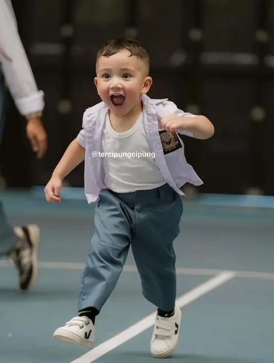 Ia mengenakan kemeja lengan pendek putih dengan logo Osis dan celana panjang abu-abu [@tercipungcipung]