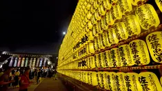 Sejumlah pengunjung melihat lentera yang memeriahkan Festival Mitama di Kuil Yasukuni, Tokyo, Jepang, (13/7). Sekitar 30.000 lentera menerangi daerah terseubt untuk mengenang korban perang.  (AFP Photo/Toru Yamanka)