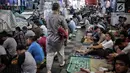 Seorang pria berjalan melintasi jemaah saat akan melaksanakan salat Jumat di Pasar Tanah Abang, Jakarta, Jumat (10/5/2019). Area masjid yang terbatas membuat jemaah harus mengisi selasar dan lorong di area pasar untuk menjalankan salat. (Liputan6.com/Faizal Fanani)