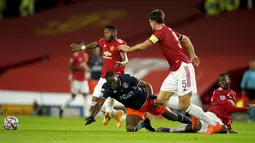 Pemain Istanbul Basaksehir Demba Ba terjatuh saat berebut bola dengan pemain Manchester United Harry Maguire pada pertandingan Grup H Liga Champions di Old Trafford, Manchester, Inggris, Selasa (24/11/2020). MU memuncaki Grup H usai menang 4-1 atas Istanbul Basaksehir. (AP Photo/Dave Thompson)