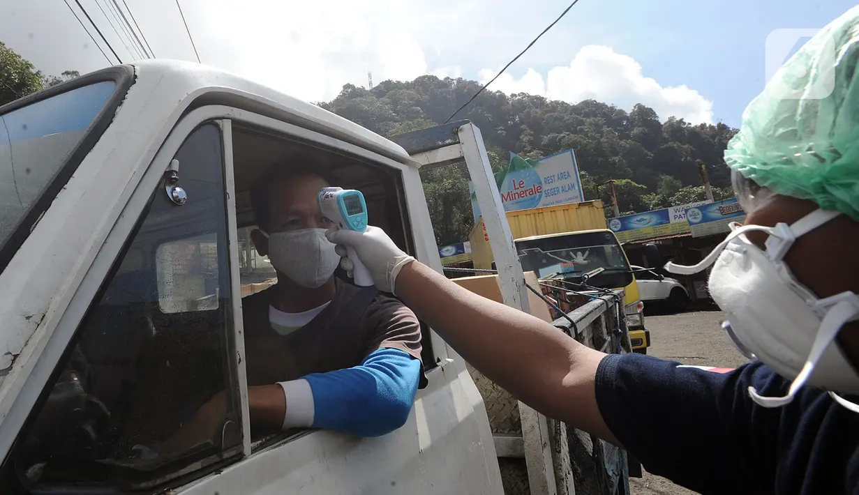 Petugas mengecek suhu tubuh pengendara saat penyekatan arus lalu lintas di Ciloto, Cianjur, Jawa Barat, Jumat (17/4/2020). Pemkab Cianjur melakukan pengecekan suhu tubuh dan penyemprotan disinfektan di titik keluar-masuk Cianjur untuk mencegah penyebaran COVID-19. (merdeka.com/Arie Basuki)