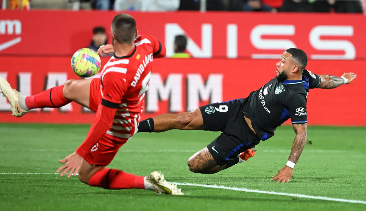 Pemain Atletico Madrid Memphis Depay (kanan) bersaing memperebutkan bola dengan pemain Girona David Lopez pada pertandingan sepak bola Liga Spanyol di Stadion Montilivi, Girona, Spanyol, 13 Maret 2023. Gol tunggal Alvaro Morata membawa Atletico Madrid mengalahkan Girona. (LLUIS GENE/AFP)