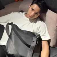 Mingyu dari Seventeen mengenakan tas Dior koleksi Vertical Hobo Bag. Ia memadukannya dengan kaos putih dipadukan celana hitam. [Dior]