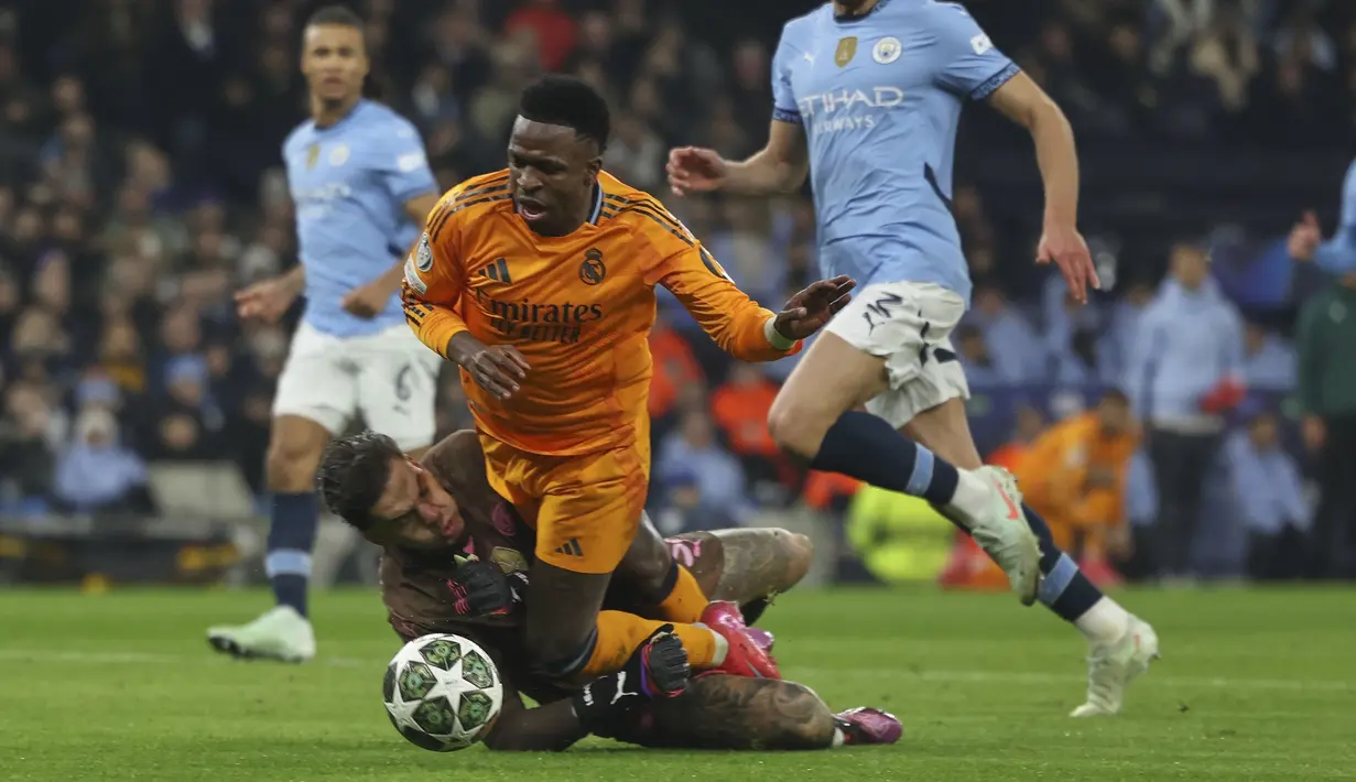 Pemain Real Madrid, Vinicius Junior jatuh saat terjegal kiper Manchester City, Ederson dalam laga leg 1 babak playoff Liga Champions 2024/2025 di Etihad Stadium, Manchester, Inggris, Rabu (12/02/2025) WIB. (AP Photo/Darren Staples)