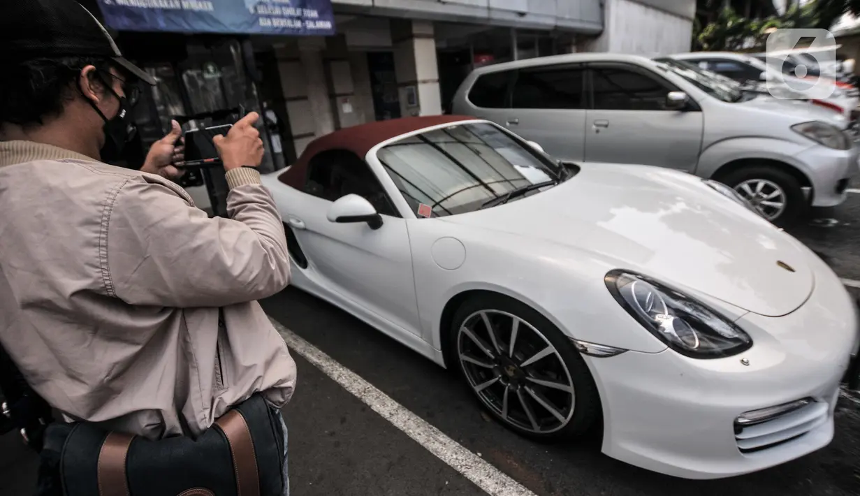 Awak media mengambil gambar mobil Porsche saat disita di Kantor Ditlantas Polda Metro Jaya, Jakarta, Senin (26/4/2021).Pemilik nobil tersebut melakukan pelanggaran menerobos jalur Transjakarta di kawasan Pondok Indah serta menghebohkan media sosial pada 18 April lalu. (merdeka.com/Iqbal S. Nugroho)