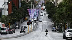 Seorang pria melintasi Saint Georges Terrace, jalan raya utama kota di Perth (29/6/2021). Beberapa kasus positif virus corona Covid-19 telah menyebabkan empat hari penguncian wilayah metropolitan Perth. (AFP/Trevor Collens)