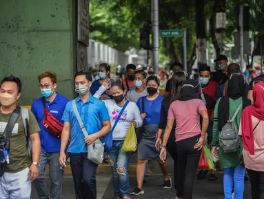 Orang-orang yang mengenakan masker menyeberang jalan di Manila, sehari sebelum pihak berwenang mencabut perintah tinggal di rumah pada Selasa (7/9/2021). Filipina akan mencabut lockdown di ibu kota Manila pada Rabu (8/9), saat kasus corona harian naik dua kali lipat. (Ted ALJIBE/AFP)