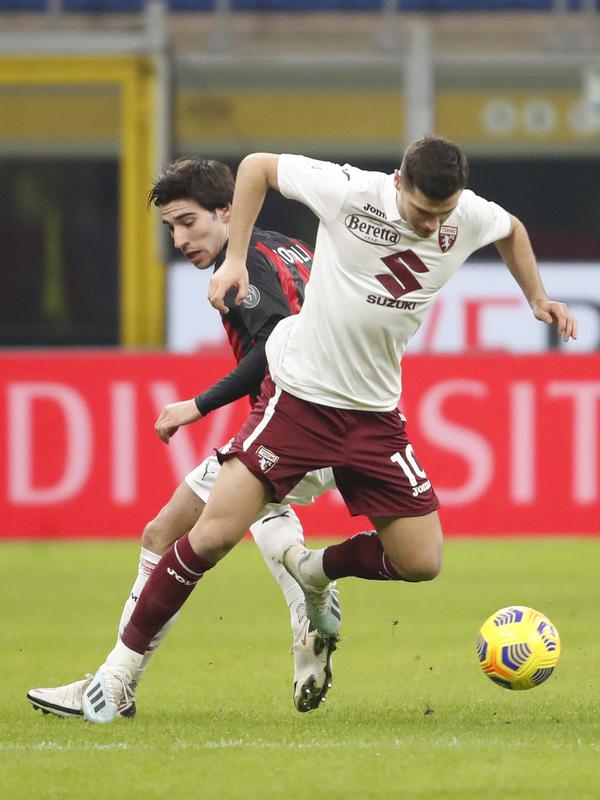 Gelandang AC Milan, Sandro Tonali berebut bola dengan gelandang Torino, Amer Gojak pada babak 16 besar Coppa Italia 2020/2021 di San Siro, Rabu (13/1/2021) dini hari WIB. Laga terkunci 0-0, AC Milan menang 5-4 atas Torino di babak adu penalti. (AP Photo/Antonio Calanni)