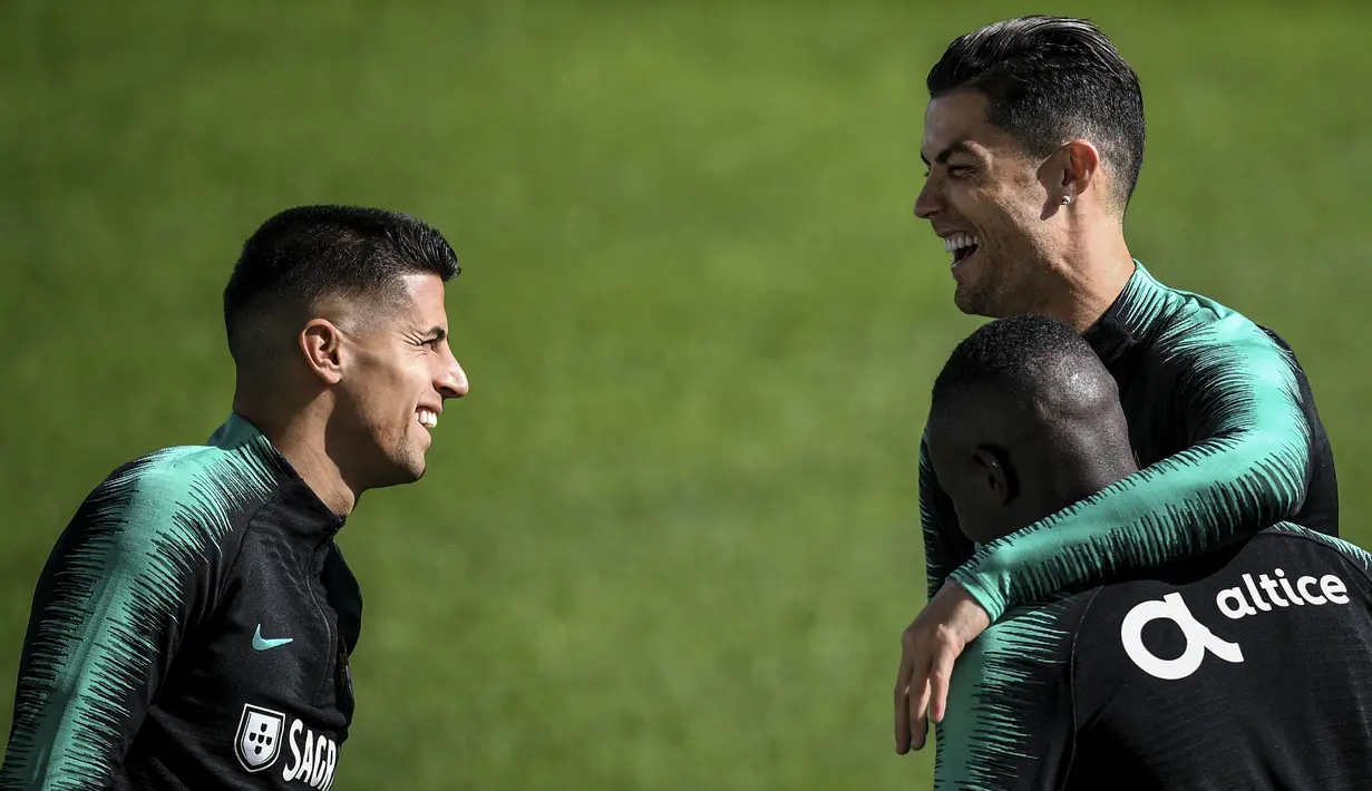 Penyerang Portugal, Cristiano Ronaldo tertawa dengan bek Joao Cancelo dan Bruma Bangna  selama mengikuti latihan tim di stadion Algarve di Faro (13/11/2019). Portugal akan bertanding melawan Lithuania pada Grup B Kualifikasi Piala Eropa 2020 di Estádio Algarve. (AFP Photo/Patricia De Melo Moreira)