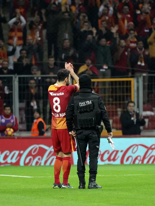 Pemain Galatasaray, Yasin Oztekin melakukan selebrasi bersama petugas polisi setelah mencetak gol saat melawan Gaziantepspor dalam Liga Super Turki di Istanbul, Minggu (11/12). (AFP PHOTO/STR)