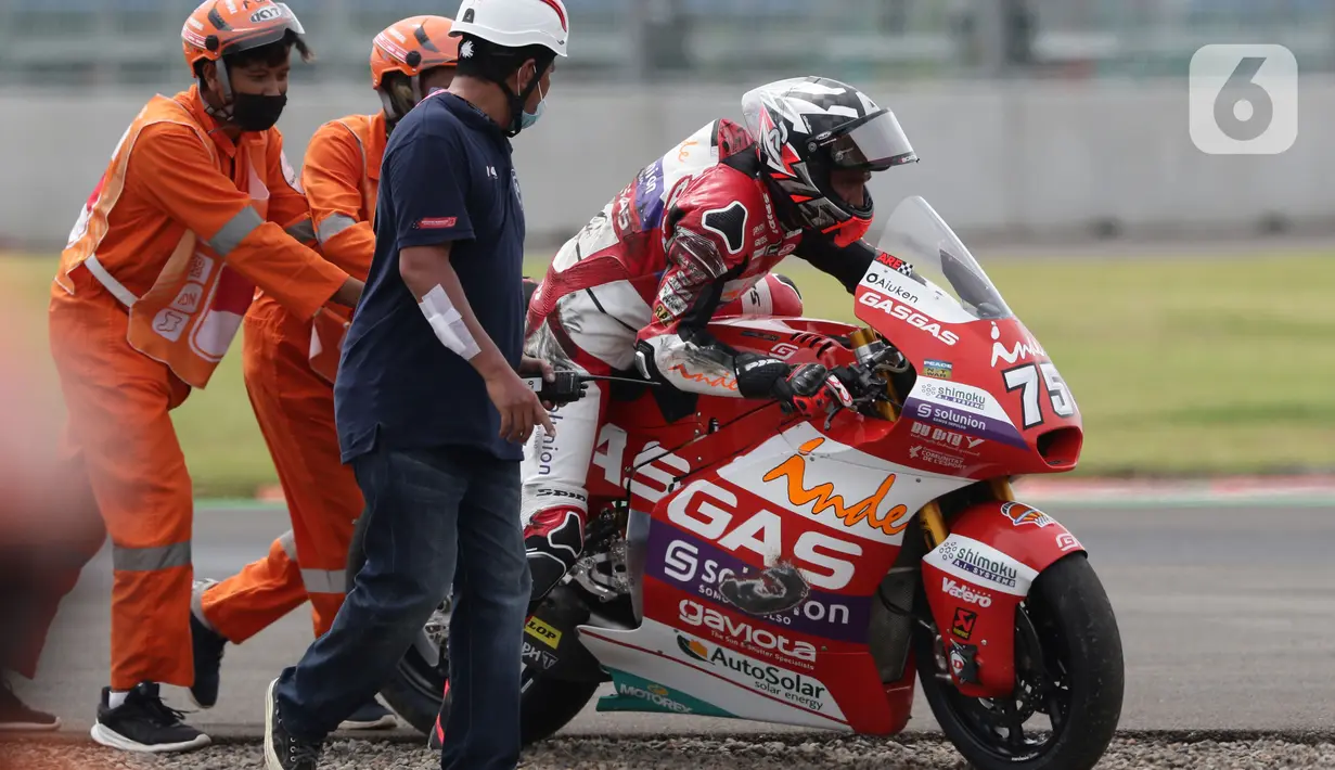 Marshal mendorong motor pembalap Albert Arenas saat kualifikasi Moto2, Pertamina Mandalika International Street Sirkuit, Lombok, Sabtu (19/3/2022). Flag Marshals bertugas memberikan sinyal peringatan kepada pembalap tentang potensi bahaya. (Liputan6.com/Helmi Fithriansyah)