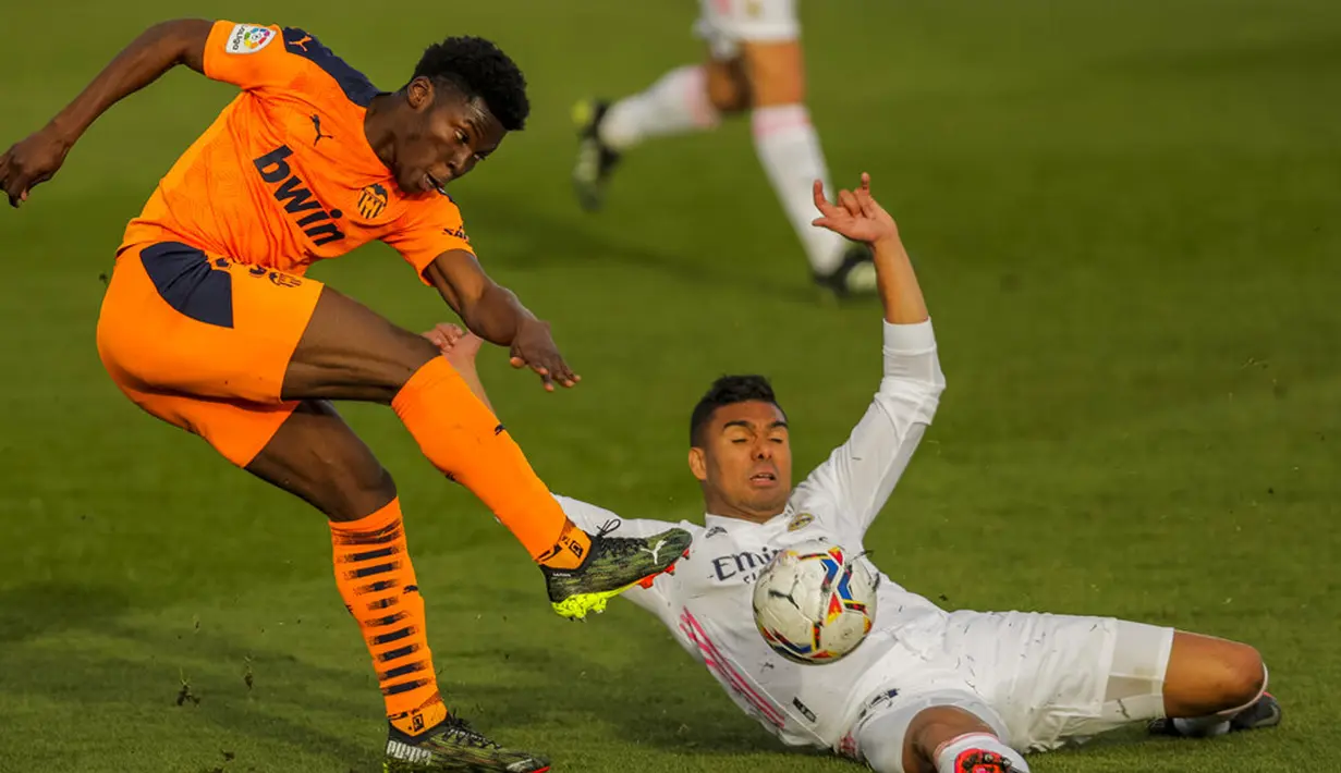 Pemain Valencia Yunus Musah (kiri) menendang bola di samping pemain Real Madrid Casemiro pada pertandingan Liga Spanyol di Stadion Alfredo Di Stefano, Madrid, Spanyol, Minggu (14/2/2021). Madrid menggeser Barcelona di peringkat dua klasemen usai menaklukkan Valencia 2-0. (AP Photo/Manu Fernandez)