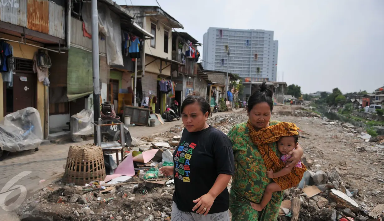 Warga berjalan di sisa gusuran bangunan di Kali Sekretaris, Kampung Rawa, Jakarta, Selasa (17/11). Warga menyesalkan sikap Gubernur Ahok yang pernah menjanjikan tidak akan ada penggusuran sebelum mendapat kunci rumah susun. (Liputan6.com/Gempur M Surya)
