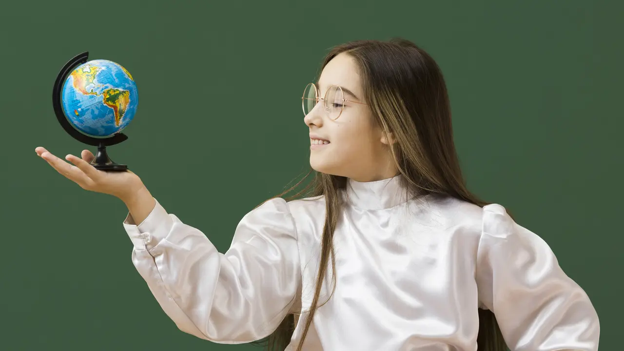 Seorang anak perempuan sedang berkacak pinggang dan memegang sebuah globe (Foto Dok: Freepik/freepik)
