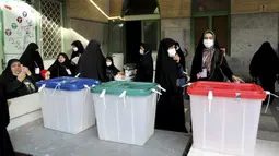 Pejabat pemilu Iran menyiapkan kotak suara di sebuah tempat pemungutan suara di Teheran, Iran, Jumat (18/6/2021). Warga Iran mulai memberikan suaranya dalam pemilihan presiden. (AP Photo/Ebrahim Noroozi)