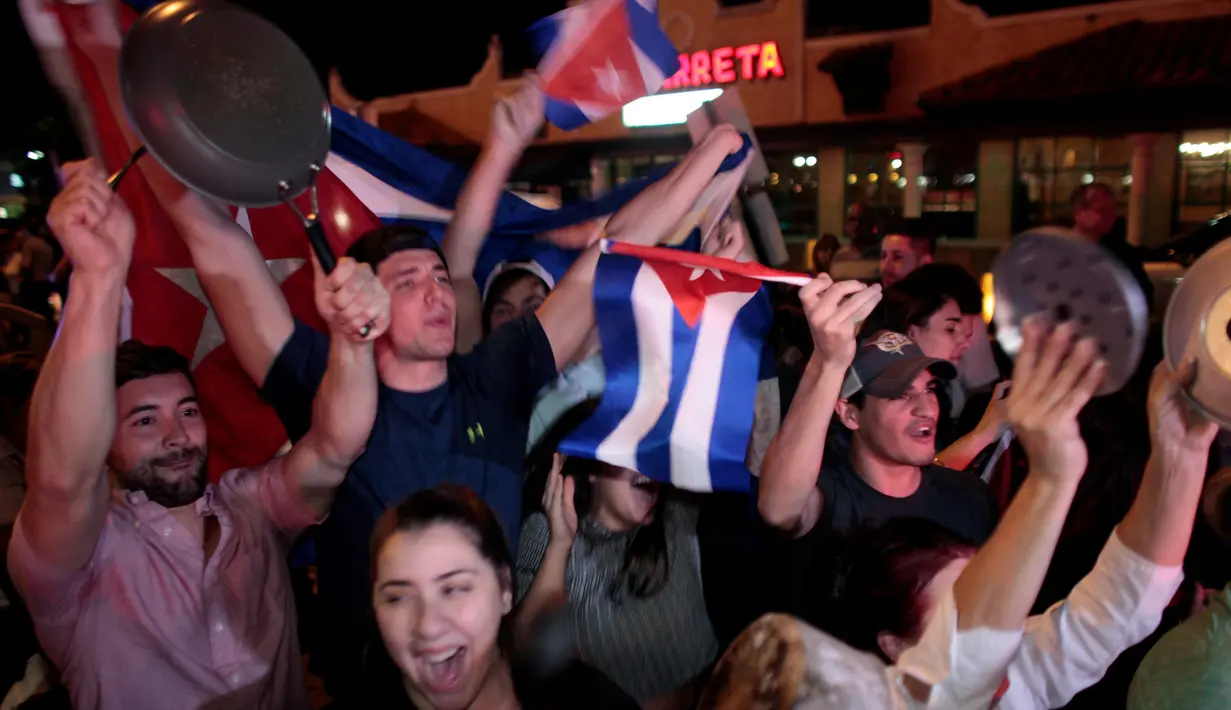 Warga Kuba bersorak saat turun ke jalan merayakan wafatnya Fidel Castro di Miami, AS (26/11). Mereka merupakan warga Kuba yang melarikan diri ke negara lain saat Castro berkuasa. (REUTERS/Javier Galeano)