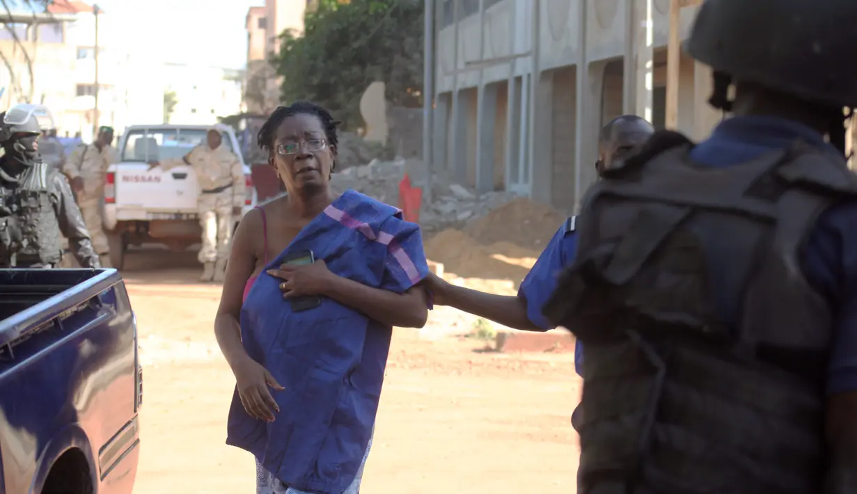 Petugas mengawal seorang sandera yang berhasil dibebaskan dari Hotel Radisson Blu di Bamako, Mali, Jumat (20/11). Kelompok militan Islam menyerbu hotel mewah tersebut dan  menyandera lebih dari 100 orang tamu serta staf hotel. (AFP PHOTO/Habibou Kouyate)
