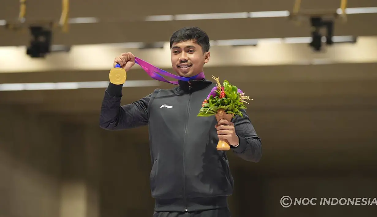 Selebrasi petembak Indonesia, Muhammad Sejahtera Dwi Putra dengan medali emas di atas podium usai memenangi lomba nomor perorangan 10 meter running target putra cabang menembak Asian Games Hangzhou 2022 di Fuyang Yinhu Sports Centre, Hangzhou, China, Senin (25/9/2023). (NOC Indonesia)