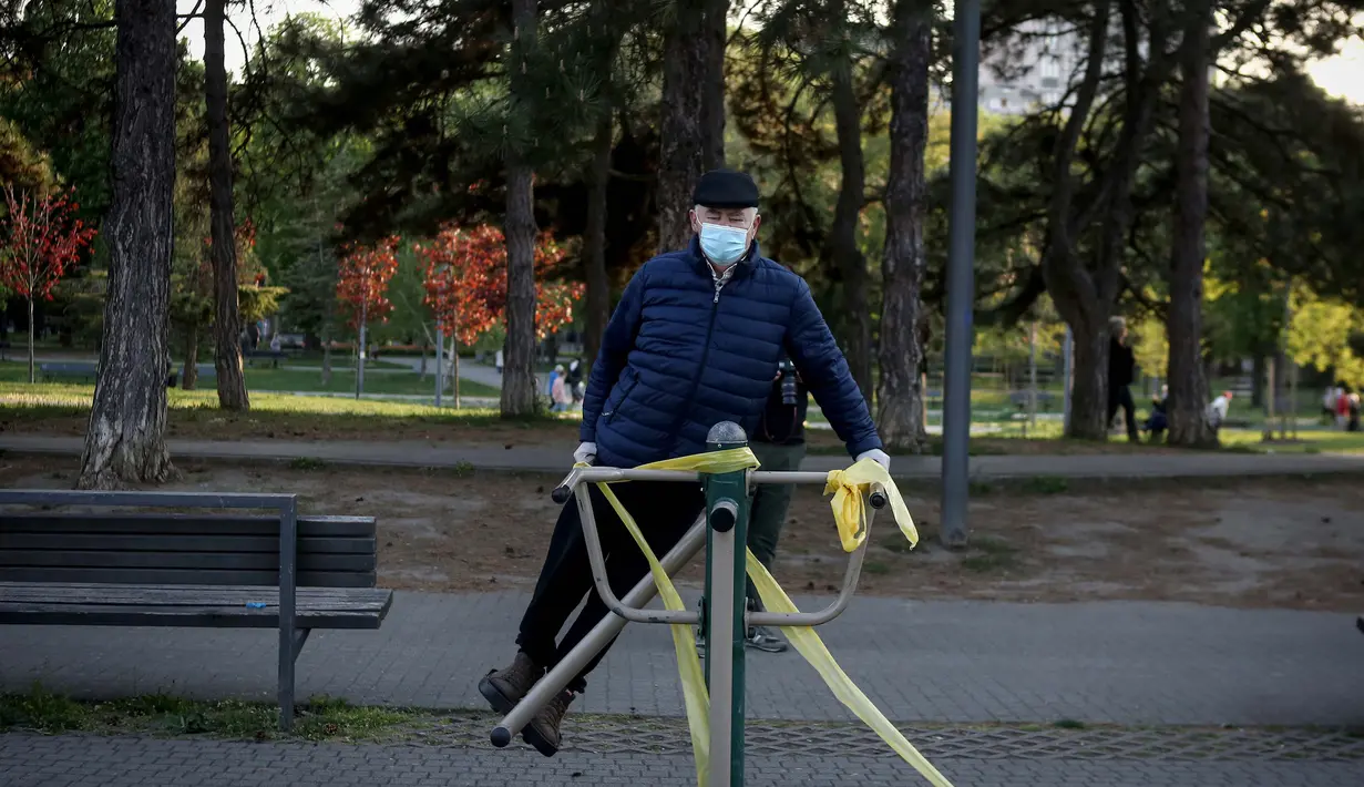 Seorang lansia berolahraga di sebuah taman di Beograd, Serbia (21/4/2020). Para lansia diberi kesempatan keluar rumah selama 30 menit pada Selasa, Jumat, dan Minggu. (AFP/Oliver Bunic)