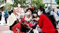 Pengunjung mengenakan masker guna melindungi diri dari virus corona berswafoto sebelum memasuki Tokyo Disneyland di Urayasu, dekat Tokyo, Rabu (1/7/2020). Tokyo Disneyland dibuka kembali untuk pertama kalinya dalam empat bulan setelah sempat ditutup karena penyebaran Covid-19. (AP/ Koji Sasahara)