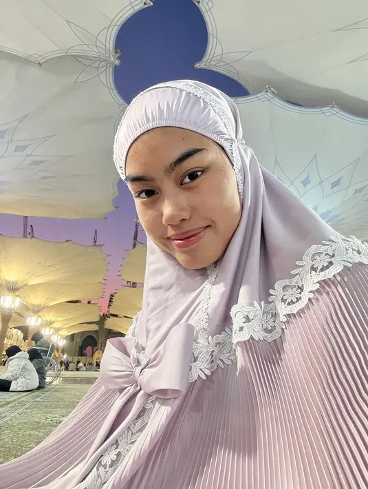 Pamer wajah polos tanpa makeup usai shalat di Masjid Nabawi, Madinah, anak sulung Alya Rohali ini ramai dipuji. Tak sedikit netizen yang bubuhkan komentar pujian untuk Jani. Namira Adjani memang dikenal sebagai anak artis yang tidak neko-neko dan selalu berpenampilan sederhana. Senyuman tipis yang dipamerkannya membuat pesonanya semakin terpancar. (Liputan6.com/IG/@namiradjani)
