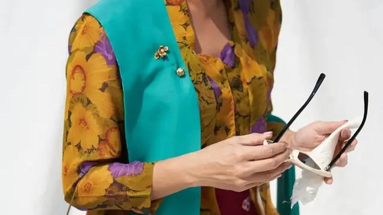 Dian Sastro tampil memukau dengan kebaya kutubaru kuning bermotif floral. Ia tambahkan sentuhan warna-warni pada sarung dan selendang hijau kebiruan yang menawan.