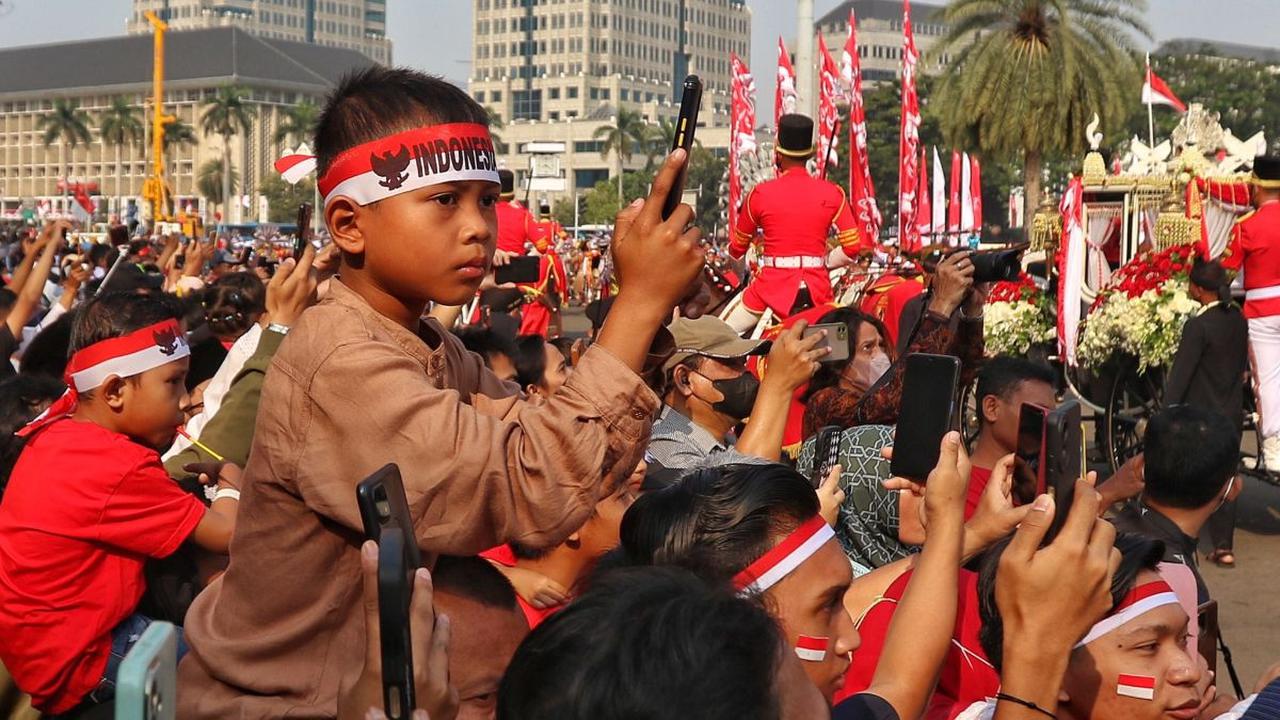 Masyarakat yang hadir di sini pun tampil dengan memakai pernak-pernik bernuansa merah putih 17 Agustus.

Salah satunya seperti kain ikat kepala merah putih ini. Mereka memakainya selama menyaksikan kirab.