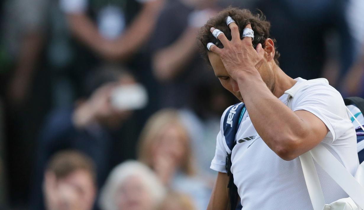 Petenis Spanyol, Rafael Nadal, mengusap rambutnya sambil meninggalkan lapangan setelah dikalahkan Giller Muller (Luksemburg) di perempat final Wimbledon 2017, Senin (10/7). Nadal menyerah dari Mueller usai melewati pertarungan lima set. (AP/Tim Ireland)