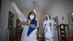 Akuntan Brasil Tercio Galdino (66) dan istrinya Alicea Galdino mengenakan pakaian pelindung mirip astronaut saat akan pergi ke Pantai Copacabana Rio de Janeiro, Brasil, 12 Juli 2020. Tercio membuat pakaian pelindung tersebut untuk melindungi dirinya dan sang istri dari COVID-19. (Mauro Pimentel/AFP)