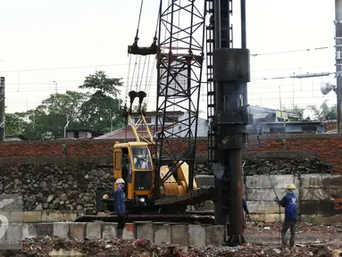Pekerja menyelesaikan pekerjaannya di bantaran Kali Ciliwung, Bukit Duri, Jakarta (1/11). Pemasangan tiang pancang untuk sheet pile di kali tersebut telah mencapai 1300 meter, ditargetkan selesai akhir Desember 2016. (Liputan6.com/Gempur M Surya)