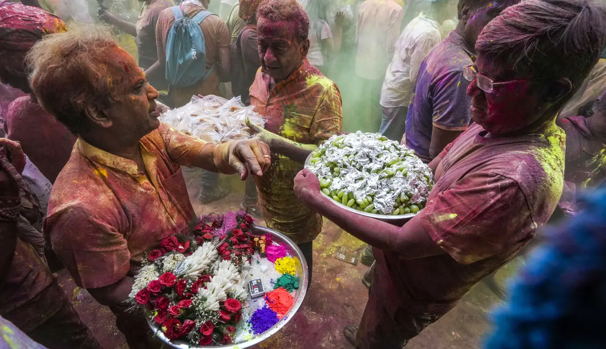 Umat Hindu dengan persembahan berjalan menuju mobil yang membawa patung dewa Krishna selama festival Holi di Kolkata, India, Minggu, 5 Maret 2023. Holi merupakan selebrasi adat umat Hindu India yang menjadi festival paling dinanti para pelancong mancanegara ketika berkunjung ke India. .(AP Photo/Bikas Das)