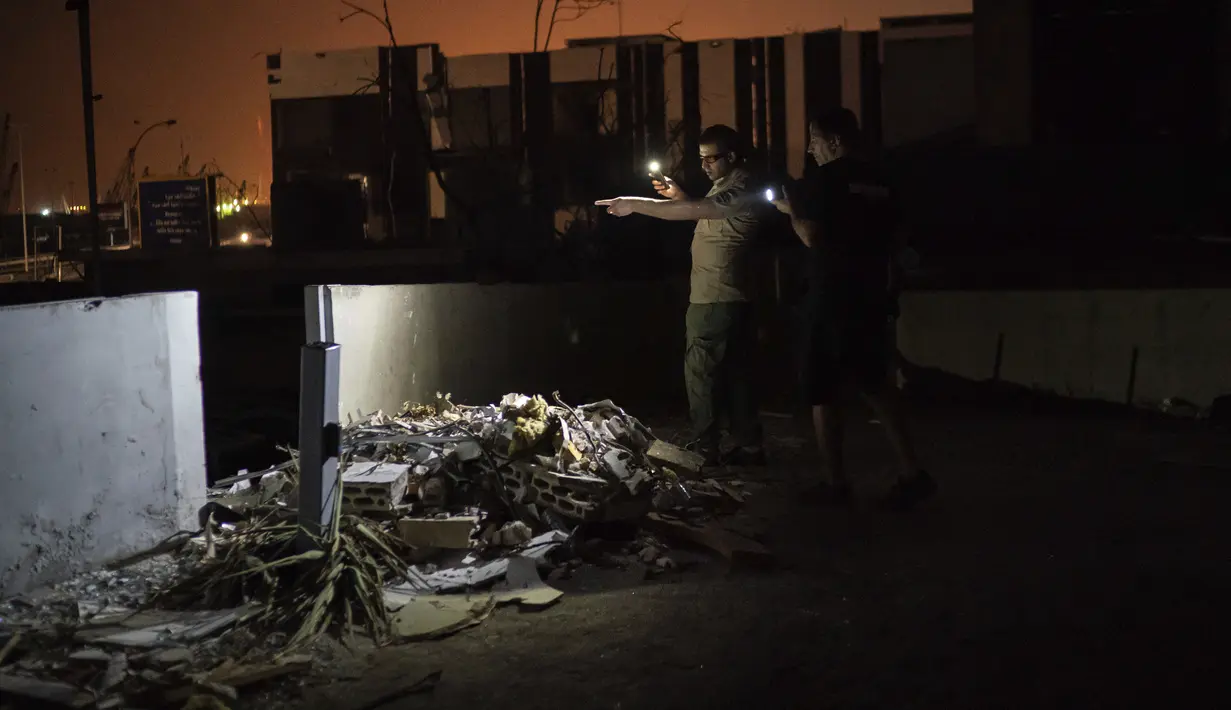 Relawan Animals Lebanon Kamal Khatib dan seorang penjaga keamanan mencari kucing yang bersembunyi di antara puing bangunan dekat lokasi ledakan besar di Beirut, Lebanon, Kamis (13/8/2020). Animals Lebanon dikerahkan untuk menyelamatkan hewan peliharaan. (AP Photo/Felipe Dana)