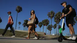 Seorang pria mengendarai Skuter listrik dari startup LimeBike di sepanjang Venice Beach, Los Angeles, 13 Agustus 2018. Anggota Dewan Los Angeles telah mengusulkan pelarangan skuter sampai peraturan dapat diselesaikan. (Mario Tama/Getty Images/AFP)