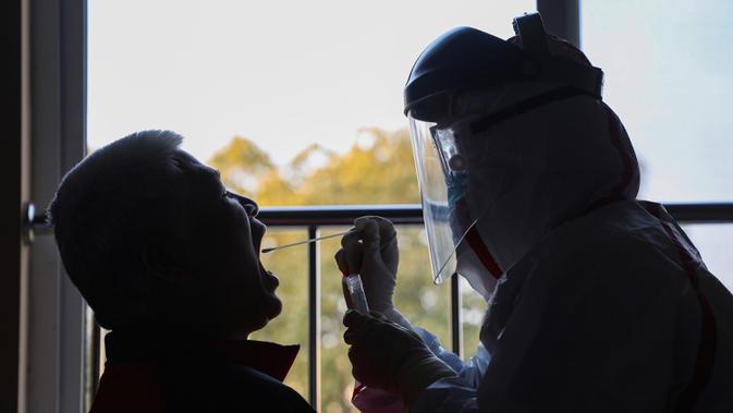 Pekerja medis berpakaian pelindung mengumpulkan sampel untuk tes asam nukleat dari pasien yang diduga terinfeksi virus corona di hotel yang digunakan dalam isolasi medis virus corona di Wuhan, Provinsi Hubei, China, Selasa (4/2/2020). (Chinatopix via AP)