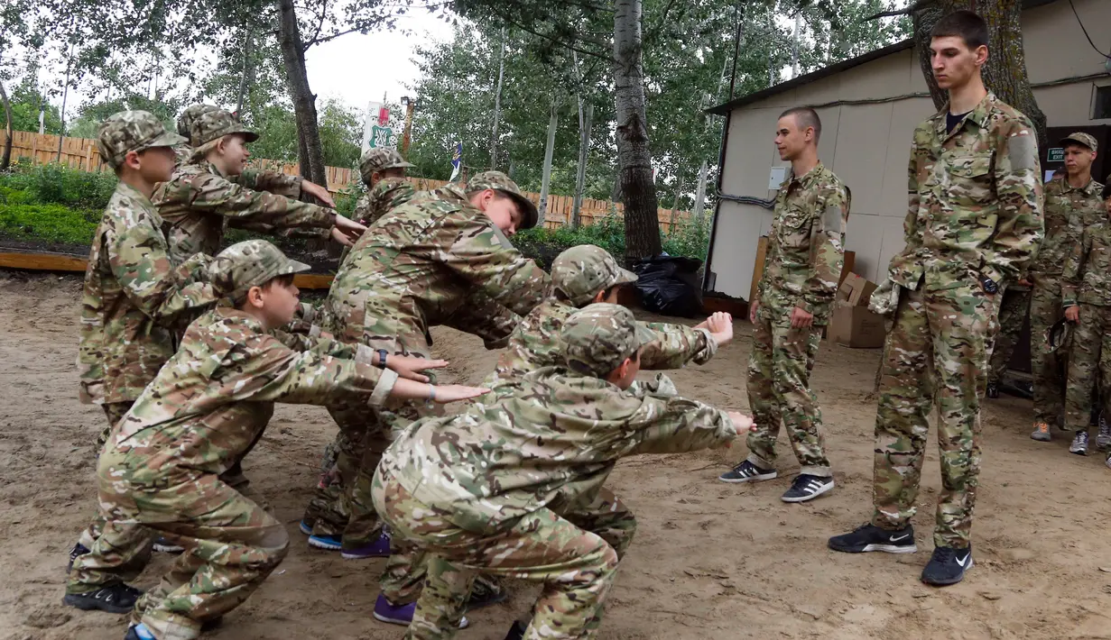 Siswa melakukan squat-up saat mengikuti pelatihan di kamp paramiliter di Kiev, Ukraina, (8/7). Konflik yang terjadi di bagian timur Ukraina membuat beberapa orang tua sangat ingin memastikan anak-anak mereka siap jika perang. (AP Photo/Efrem Lukatsky)