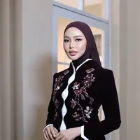 Dalam suasana penuh bunga yang bergradasi merah, putih, hingga burgundy, keduanya tampil serasi dengan busana tradisional bernuansa modern yang memancarkan kemewahan sekaligus kehangatan. [@loritayoung_mua].
