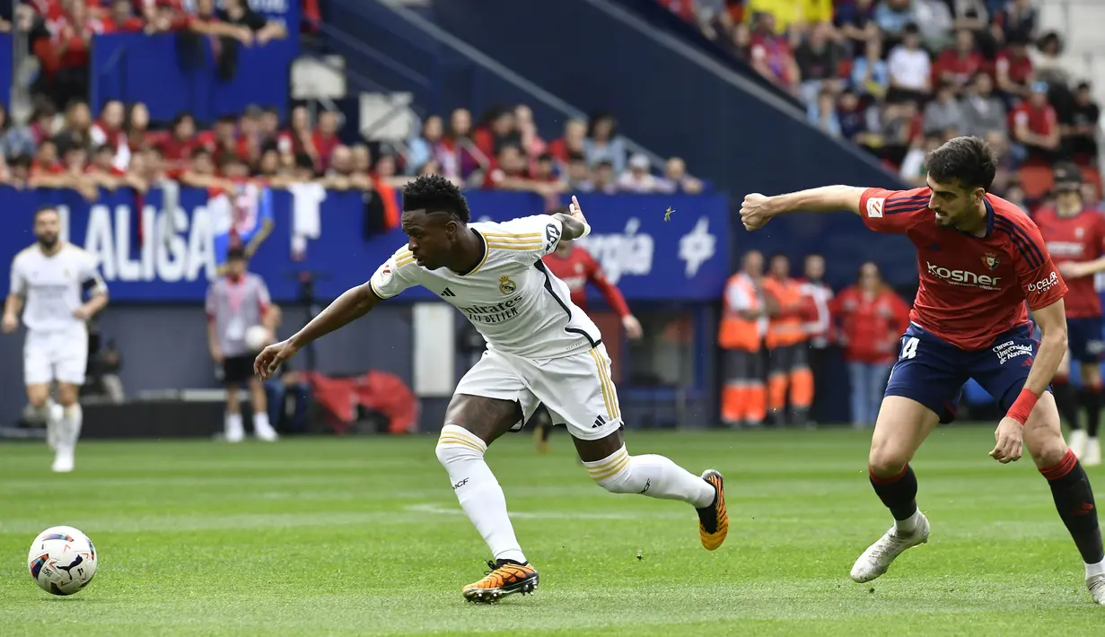 Pemain Real Madrid, Vinicius Junior, berebut bola dengan pemain Osasuna, Ruben Garcia, pada laga pekan ke-29 La Liga 2023/2024 di Stadion El Sadar, Sabtu (16/03/2024). Hasil ini membuat Real Madrid semakin perkasa di puncak klasemen sementara La Liga dengan raihan 72 angka. (AP Photo/Alvaro Barrientos)